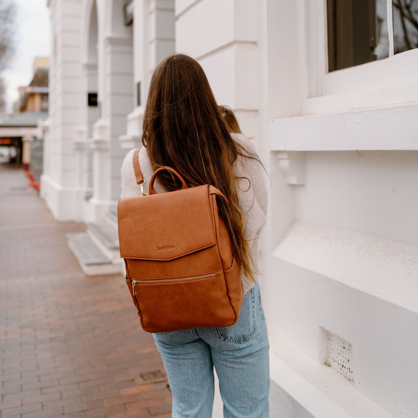 Parent wearing Florence tan Nappy Backpack showing comfortable fit for everyday use