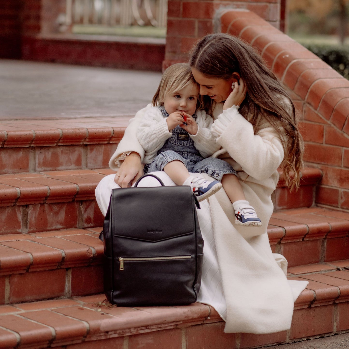 Stylish parent using Florence Black Nappy Bag while out with baby